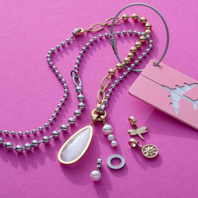 Anhänger JESSY gold Clip & Mix mit verschiedenen austauschbaren Charms auf rosa Hintergrund