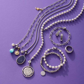 Schmuckkollektion mit Anhängern, Ketten, Armbändern und Ringen auf violettem Hintergrund