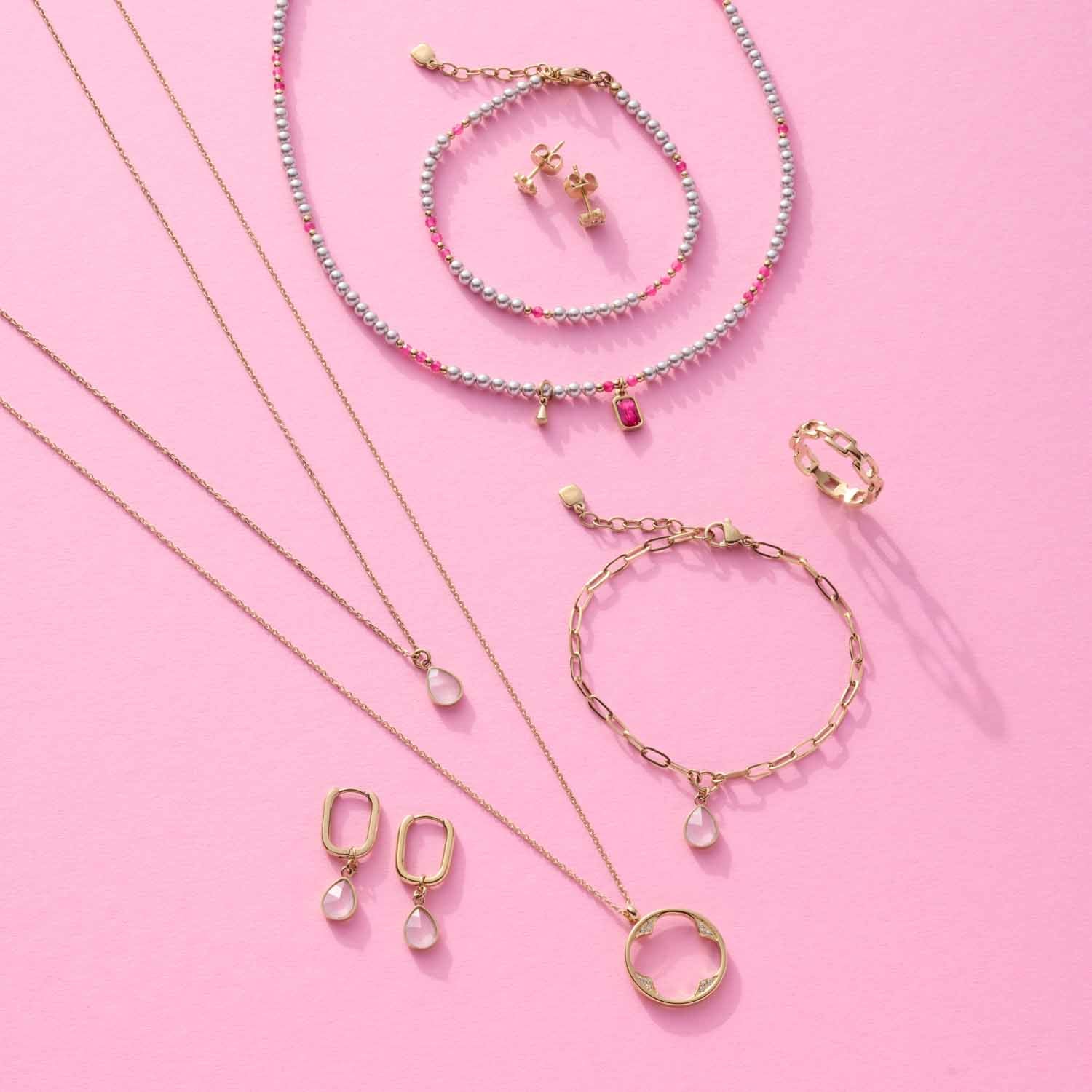 Schmuckkollektion auf rosa Hintergrund, Ohrhänger ROSY gold CIAO mit Glasperlchen, Ketten und Armbänder