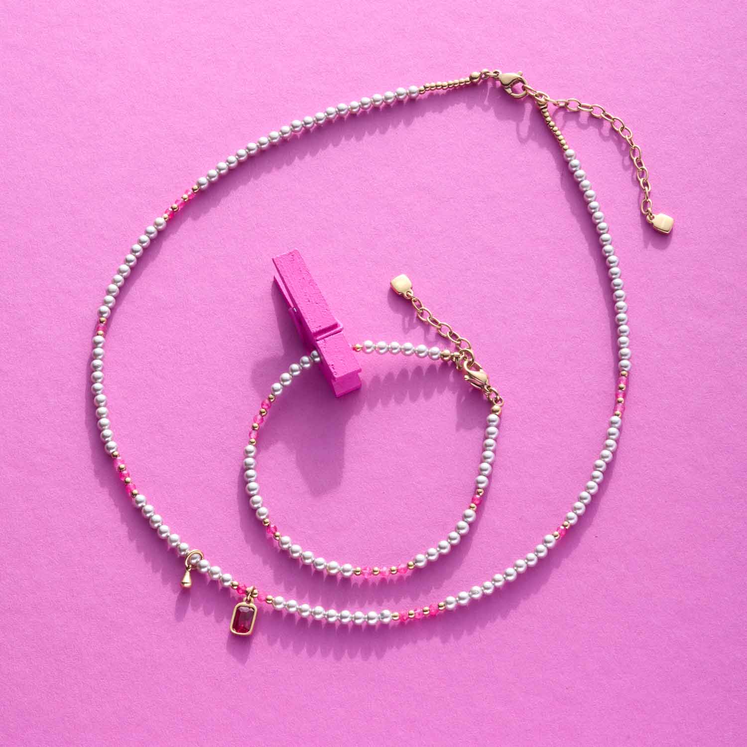 Armband PINKY gold CIAO mit Perlen und rosa Clip auf rosa Hintergrund