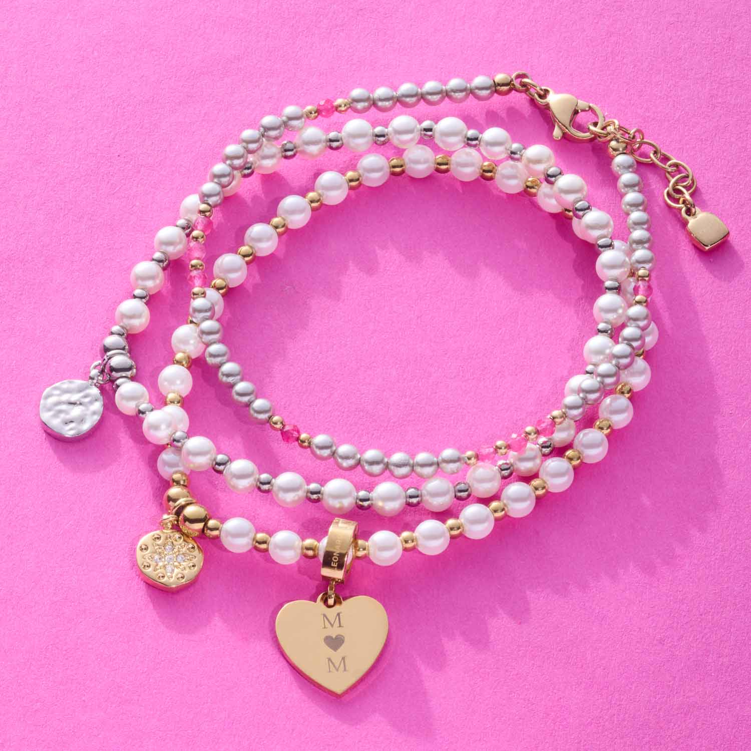 Armband PINKY gold CIAO mit Perlen und Herzanhänger auf rosa Hintergrund