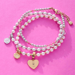 Armband PINKY gold CIAO mit Perlen und Herzanhänger auf rosa Hintergrund