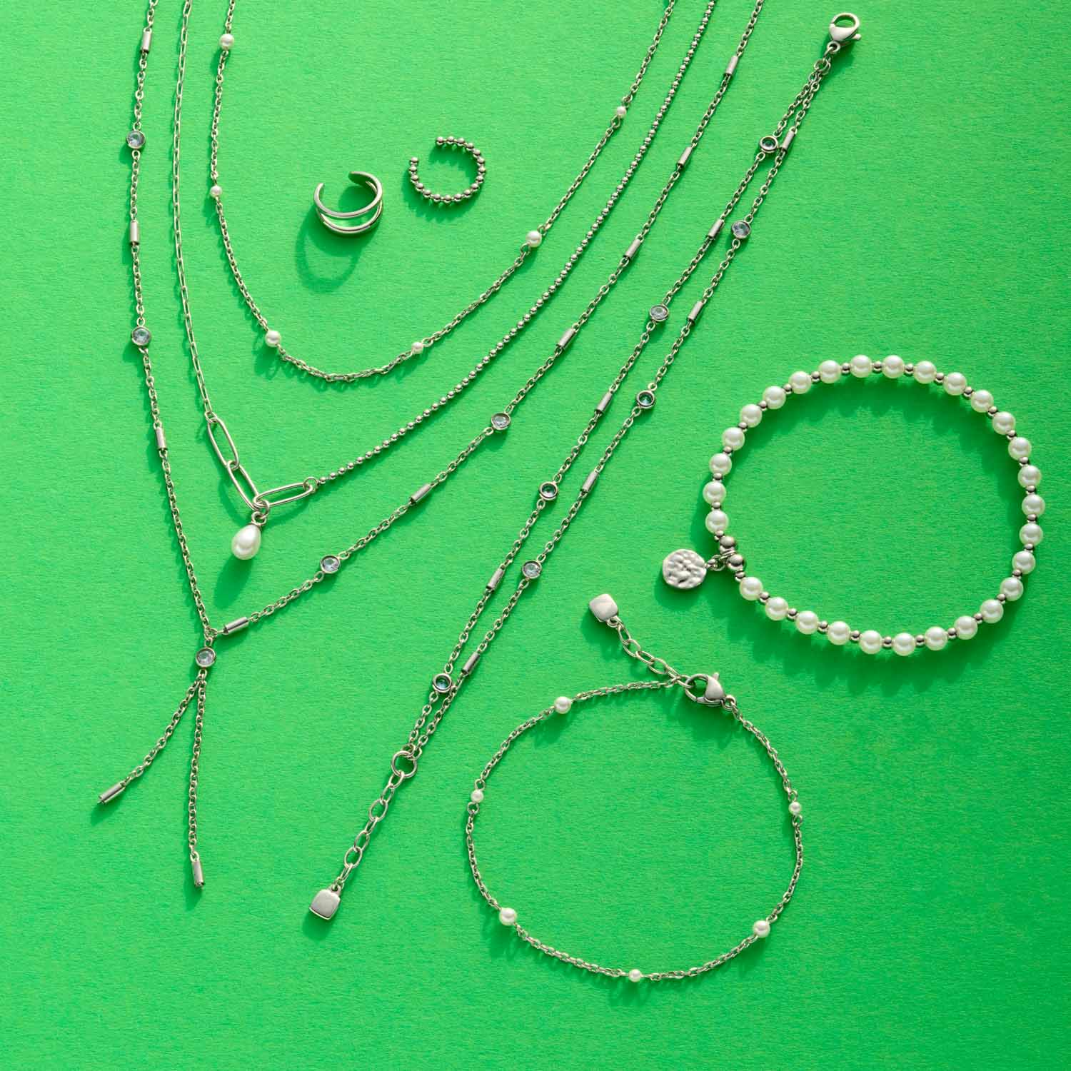 Halskette PEGGY und Armbänder aus Muscheln und Edelstahl auf grünem Hintergrund