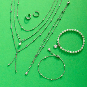 Halskette PEGGY und Armbänder aus Muscheln und Edelstahl auf grünem Hintergrund