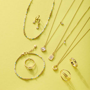 Goldene Halsketten, Ringe und Armbänder mit Zirkonium-Steinen auf gelbem Hintergrund
