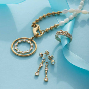 Ring BOBBY 17 gold mit Anhänger, Ohrstecker und Armband auf blauem Untergrund