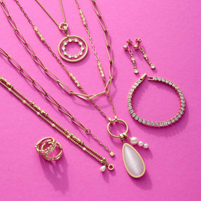 Schmuckkollektion mit Ketten, Ringen, Armband und Ohrringen auf rosa Hintergrund