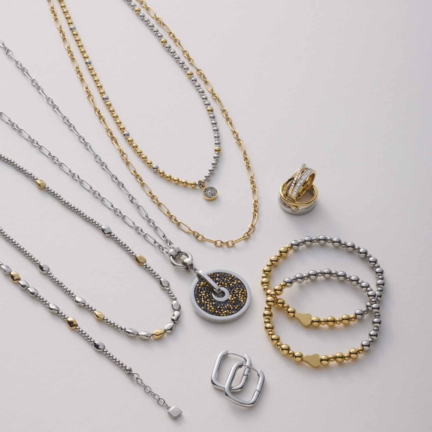 Schmuckkollektion mit Halsketten, Anhängern und Armbändern in Gold und Silber auf neutralem Hintergrund
