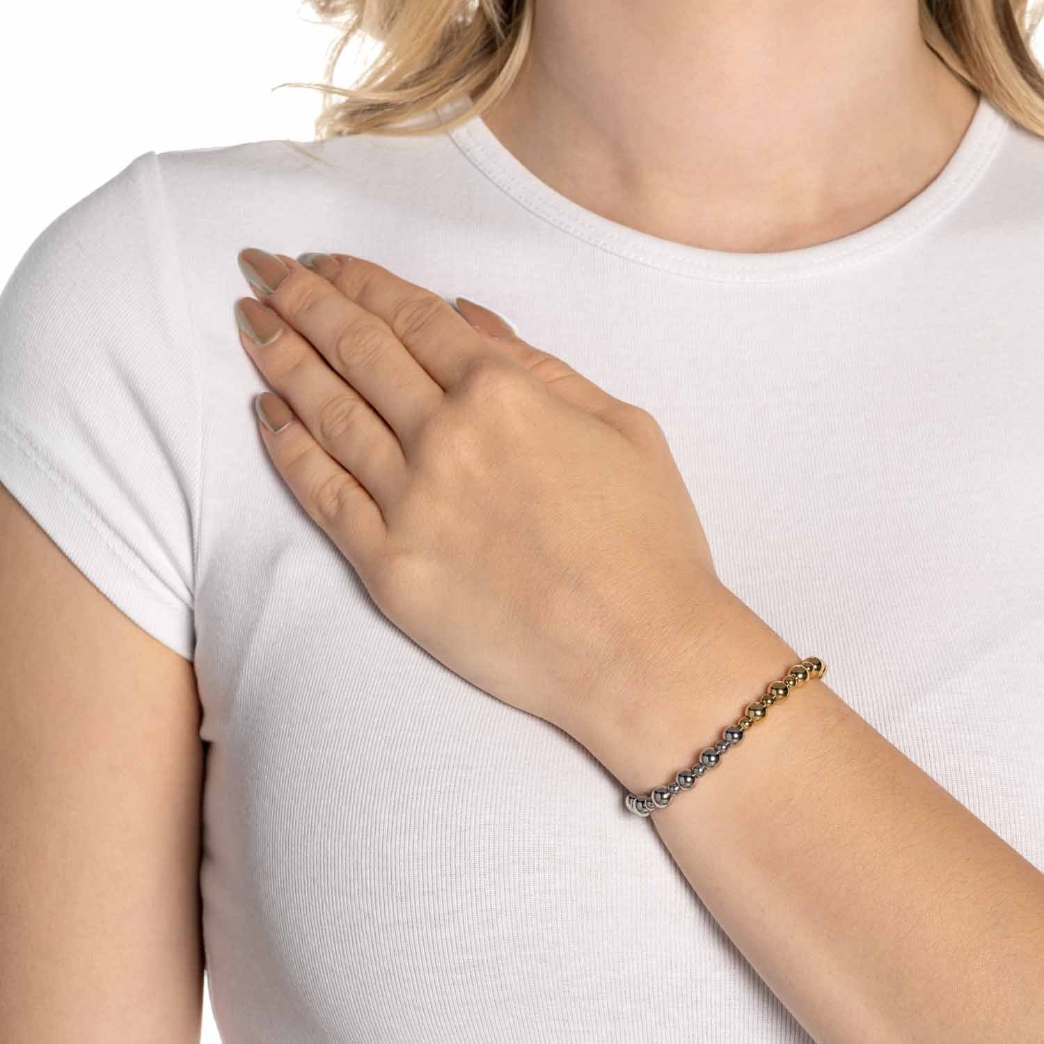 Frau traegt Armband PHILINE gold am Handgelenk, weisses T-Shirt
