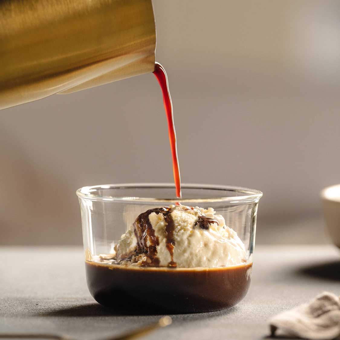 Schale VETRO mit Vanilleeis und Schokoladensauce, Eislöffel liegt bereit