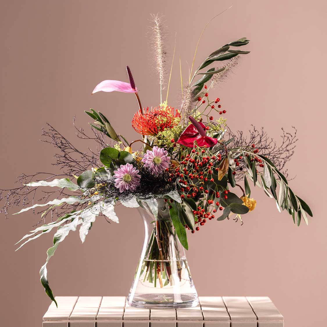 Vase GIA mit buntem Blumenstrauß auf Tisch vor rosa Hintergrund