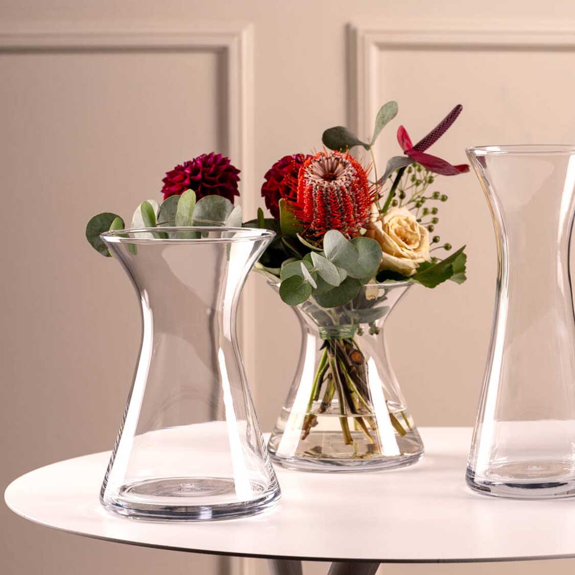 Vase GIA mit roten und cremefarbenen Blüten auf weißem Tisch