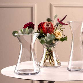 Vase GIA mit roten und cremefarbenen Blüten auf weißem Tisch