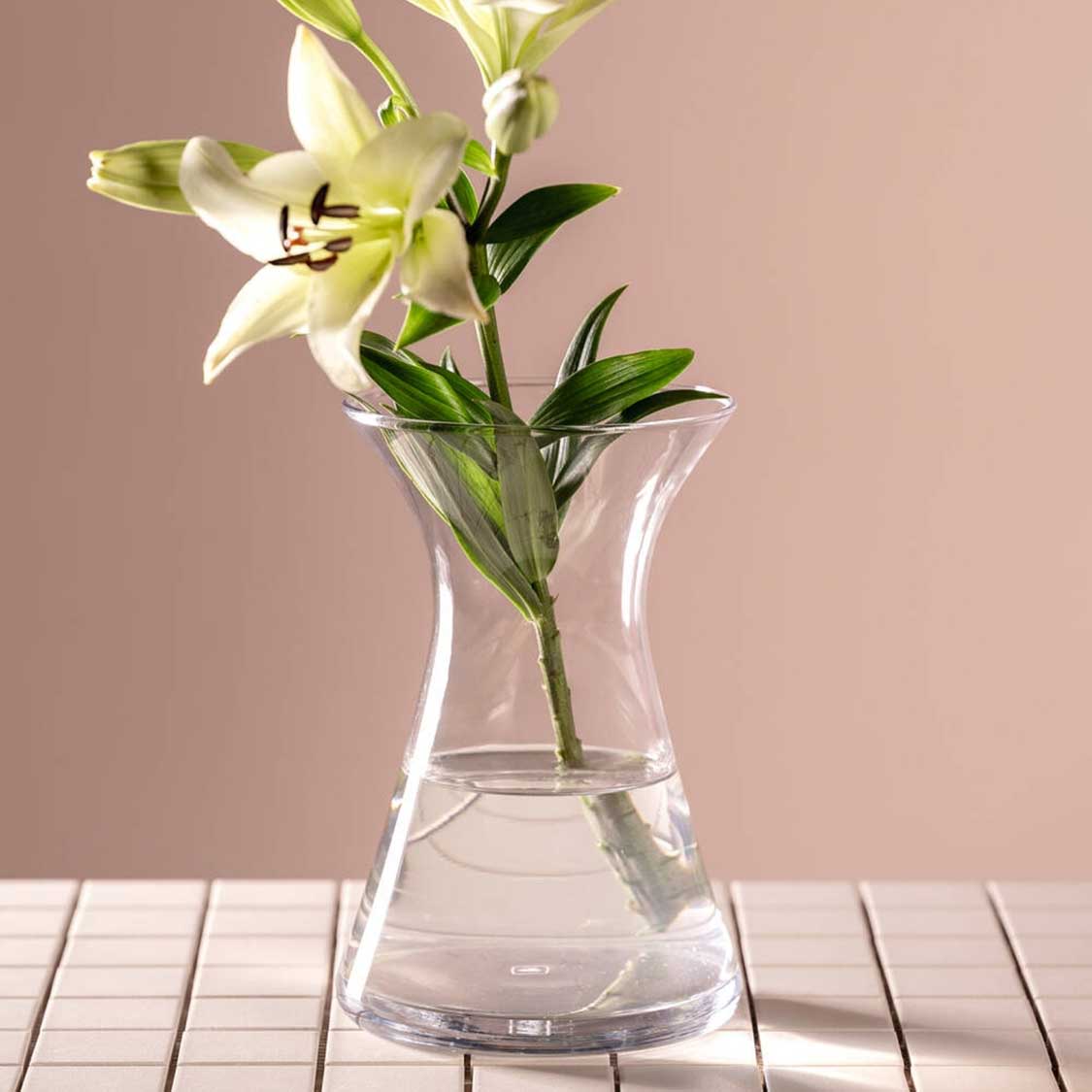 Vase GIA mit weisser Lilie und Grün auf Holztisch, beige Hintergrund