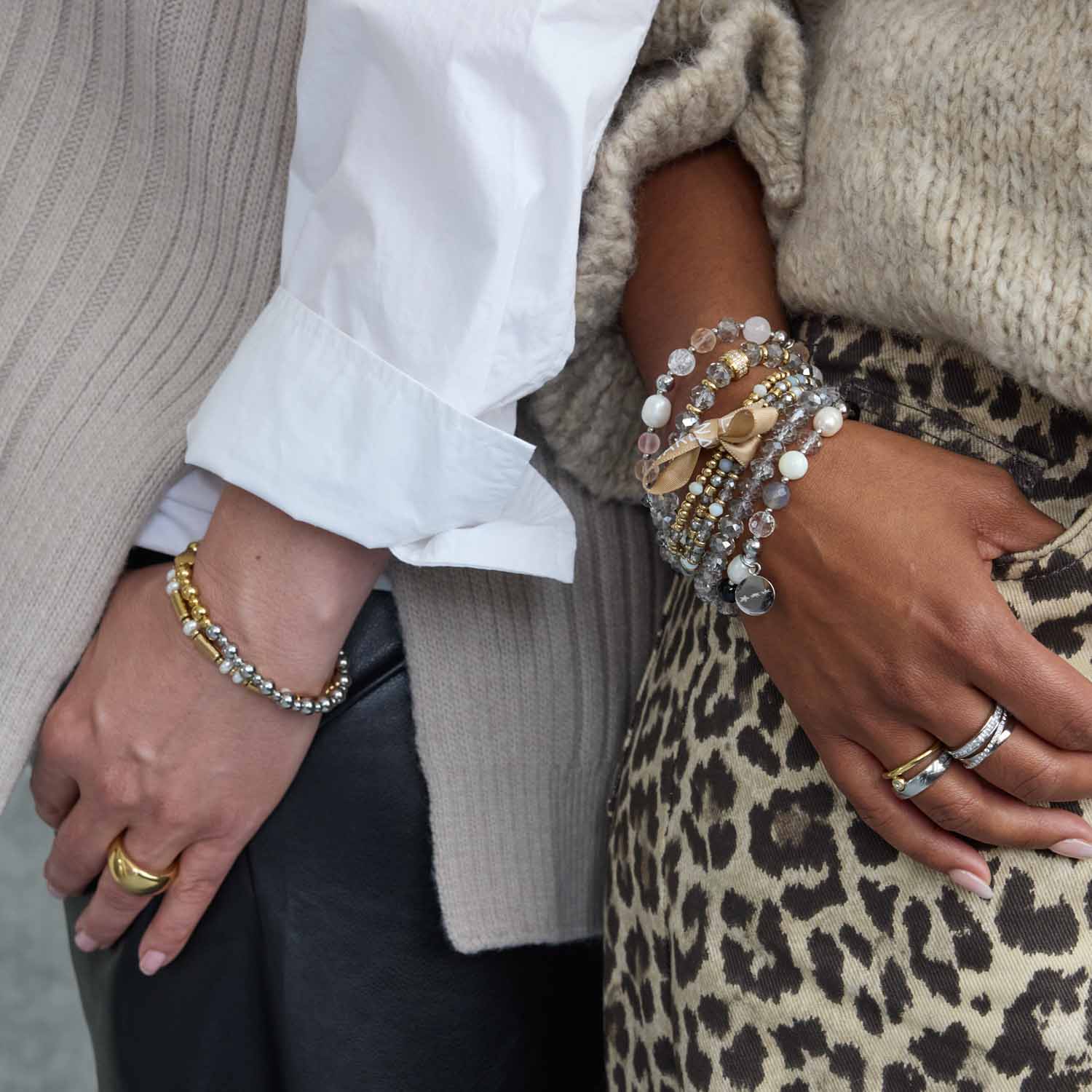 Armband NINA gold an Frauenhand neben Mannshand, Nahaufnahme
