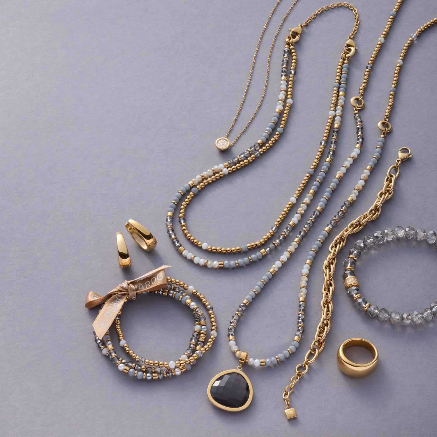 Halskette CATHERINE mit Perlen, Ringen und Anhängern auf grauem Hintergrund