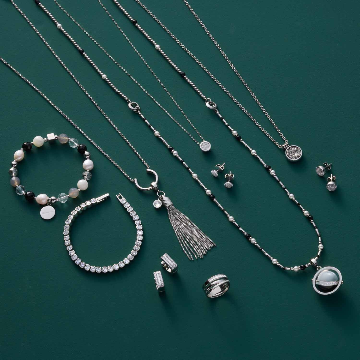 Silberner Schmuck der Serie SARAH auf grünem Hintergrund: Ketten, Armbänder, Ohrringe und Ring