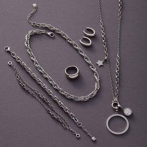 Creole ELODIE Serie in Silber, Kettenanhänger und Ringe auf grauem Hintergrund