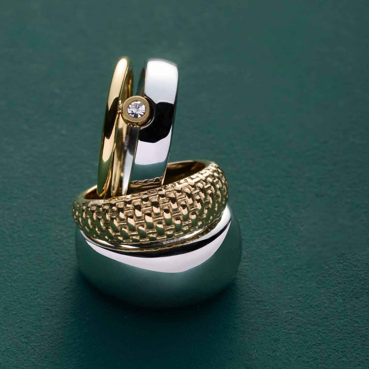 Ring GEORGETTE 19 mit goldfarbenem und silbernem Band auf grünem Untergrund