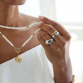 Frau traegt Ring GEORGETTE 19 an der Hand, zusammen mit Perlenkette und goldenem Anhaenger