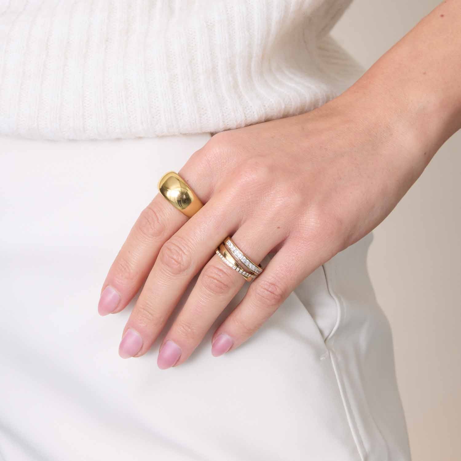 Hand mit Ring GEORGETTE 17 gold, weißes Outfit, manikürte Nägel