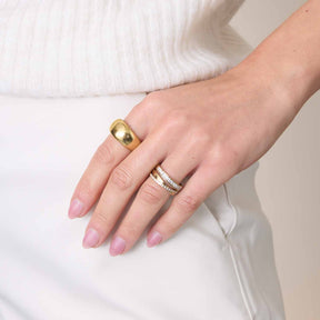 Hand mit Ring GEORGETTE 17 gold, weißes Outfit, manikürte Nägel