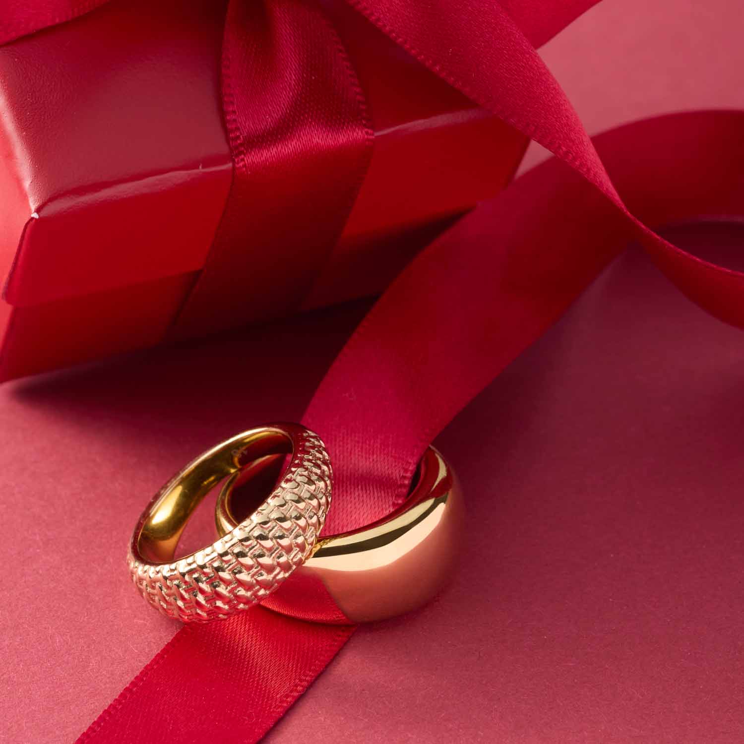 Ring PINOU 18 gold auf rotem Geschenkband und Hintergrund
