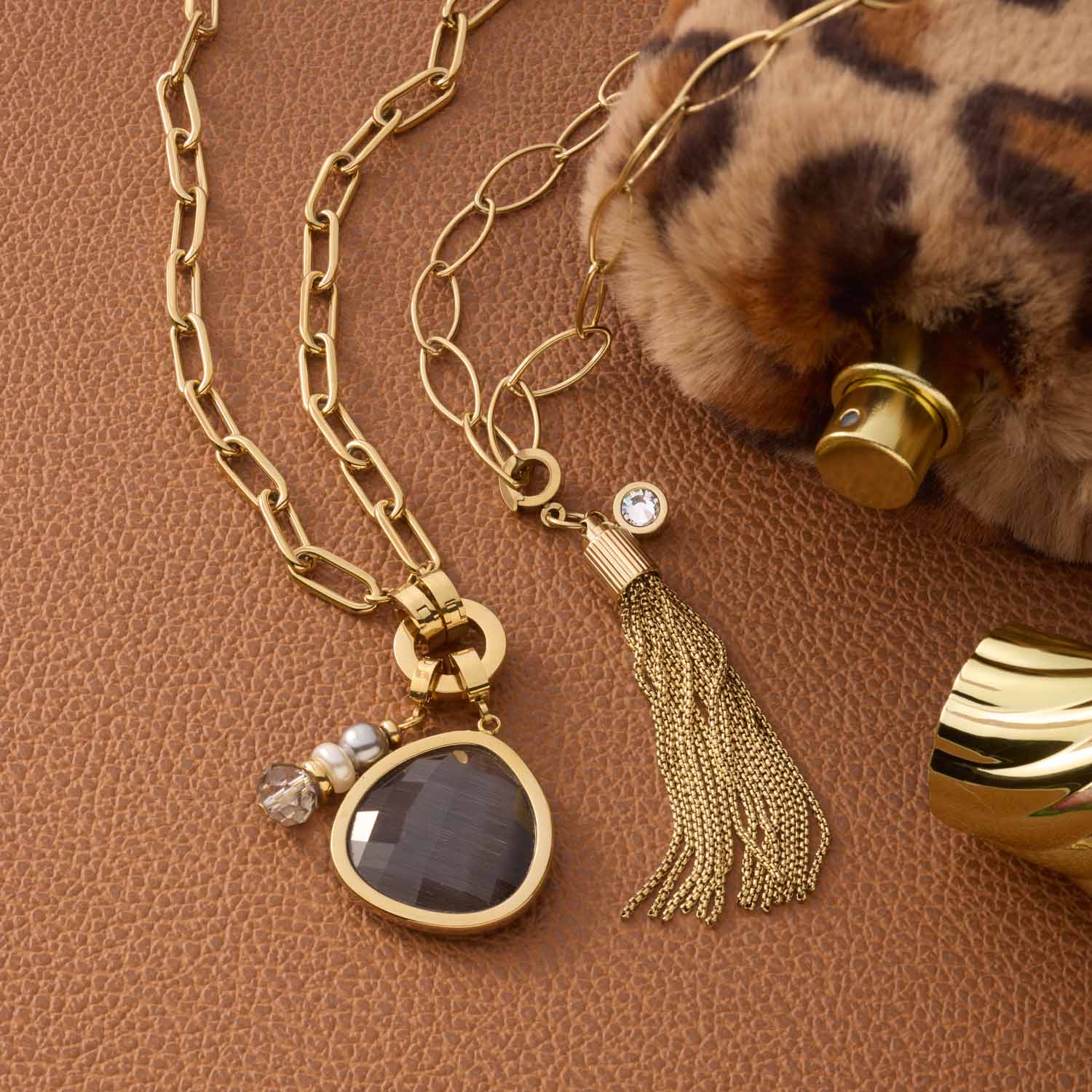 Anhänger MINA Clip & Mix gold mit Kette, Quaste und Katzenaugenstein auf braunem Untergrund mit Accessoires