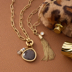 Anhänger MINA Clip & Mix gold mit Kette, Quaste und Katzenaugenstein auf braunem Untergrund mit Accessoires