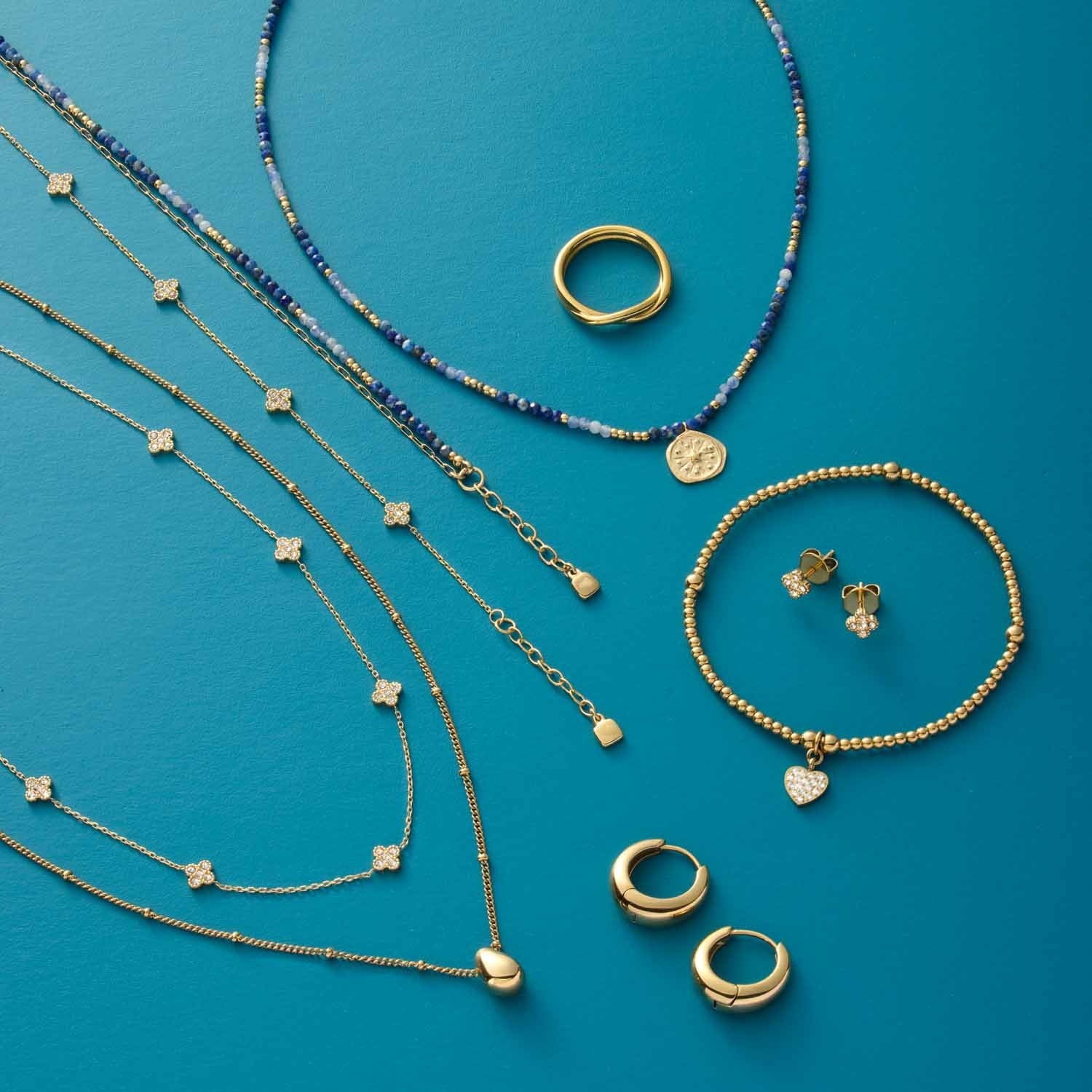 Halskette LISETTE, Ringe und Armbänder in Gold und Blau auf türkisem Hintergrund