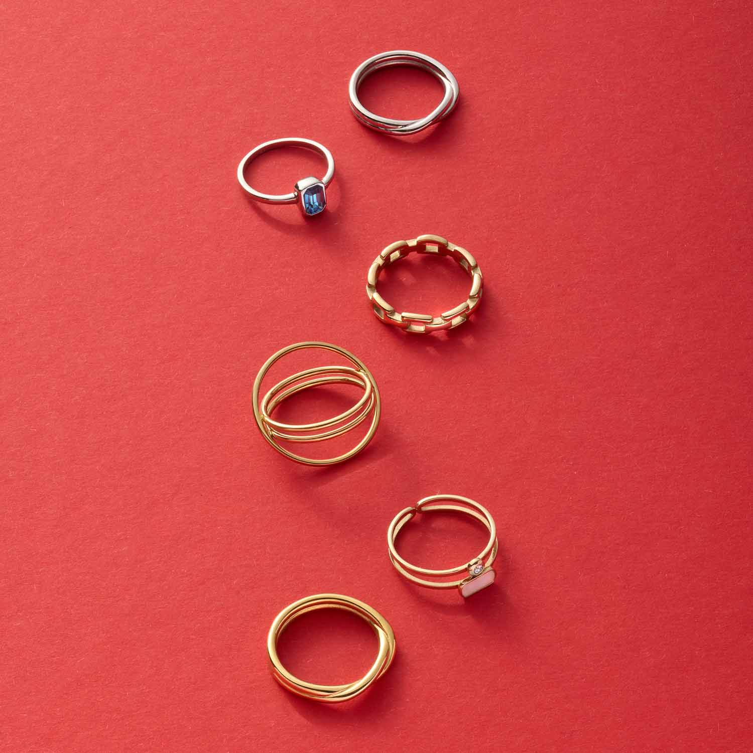 Sechs goldene und silberne Ringe auf rotem Hintergrund arrangiert