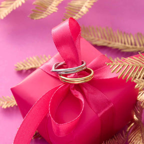 Ring TWISTER 20 gold auf rosa Geschenkbox mit Schleife und goldenen Blättern