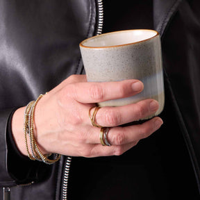 Person trägt goldene Ringe TWISTER 20 und Armbänder an der Hand