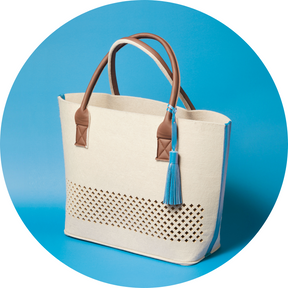 LEONARDO Beach Bag beige Papiertragetasche mit braunen Henkeln und blauem Quastenverzierung auf blauem Hintergrund