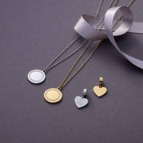 Halskette FERRARA mit Gravur in Silber und Gold auf grauem Untergrund mit weißem Band