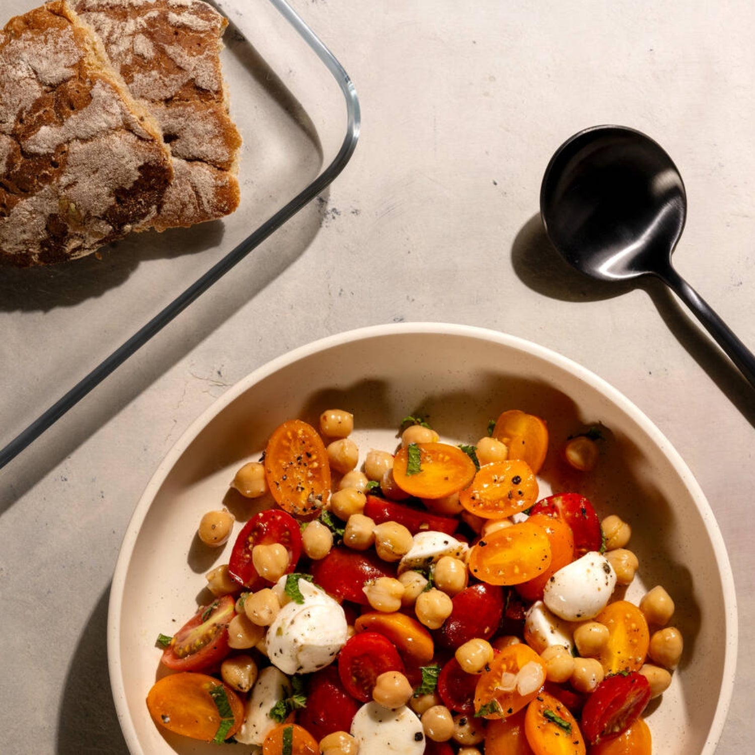 Platte CIAO mit Kichererbsen-Gemüse-Salat und Brot auf Tisch