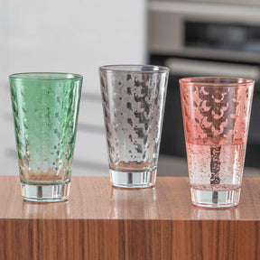 Drei Trinkgläser OPTIC mit Getränk in Grün, Grau und Rosa auf Holztisch