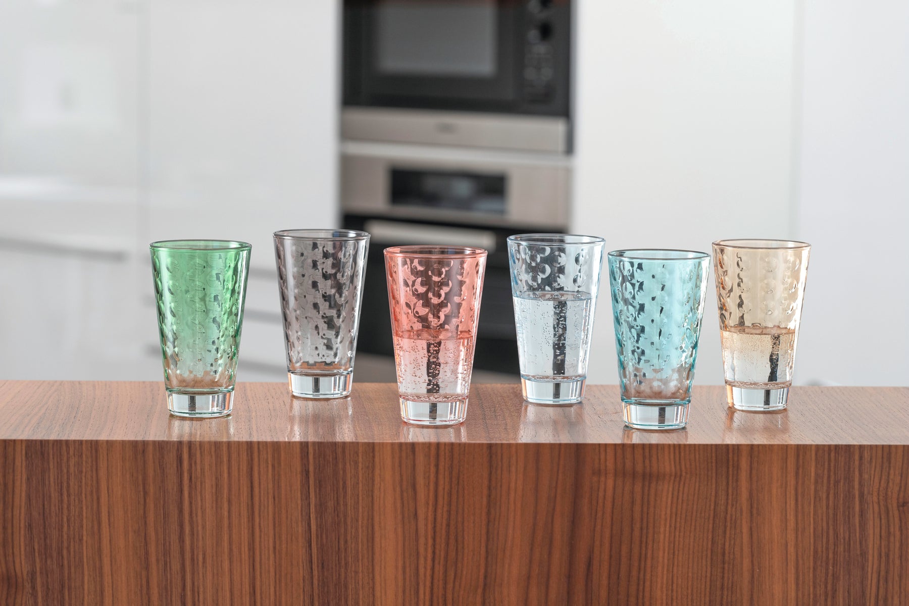 Sechs Trinkgläser OPTIC in Pastellfarben auf Holztheke in Küche