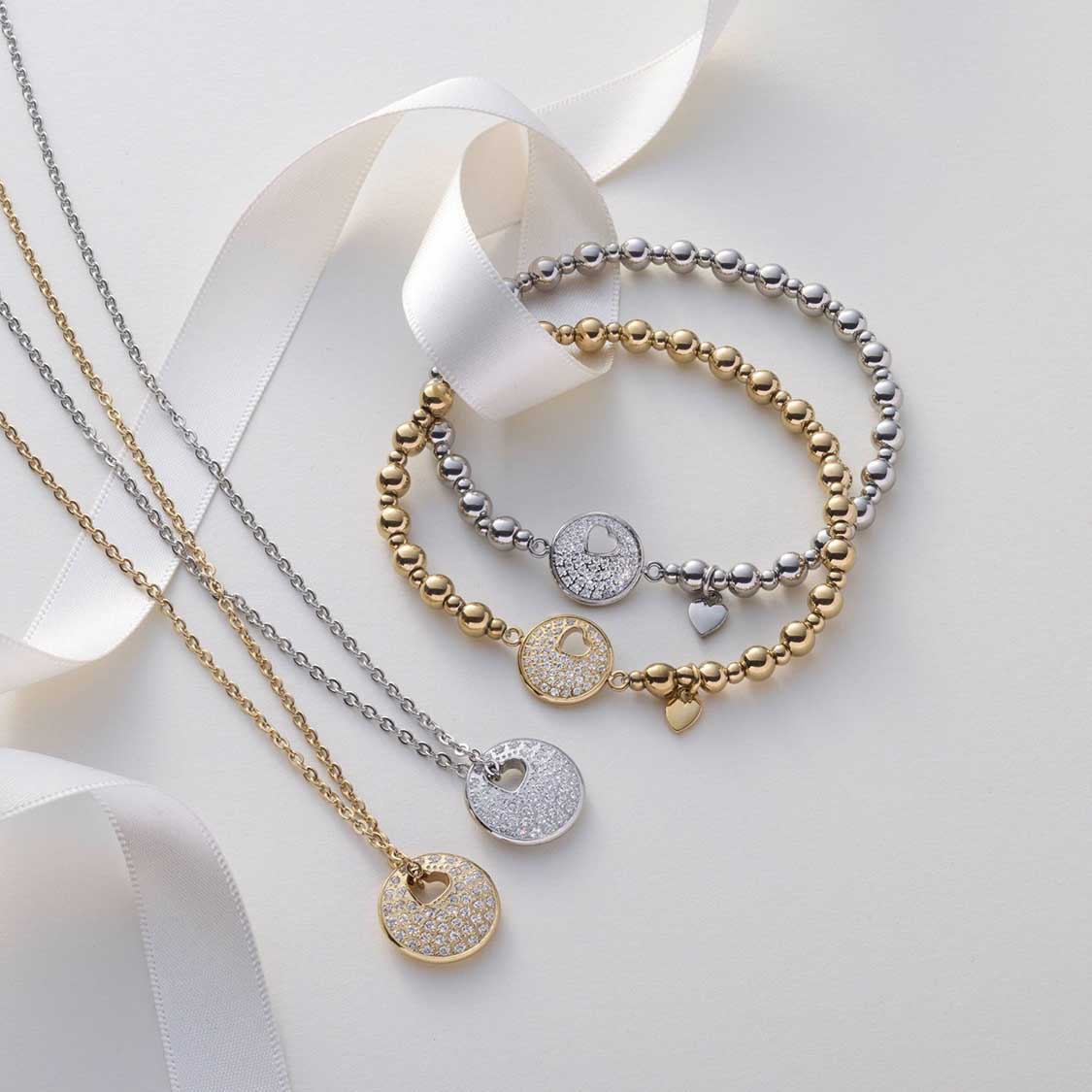 Armband SUE AMOUR gold mit Perlen und Anhängern auf weißem Hintergrund mit Bändern