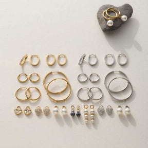 Schmuckkollektion mit goldenen und silbernen Ringen, Ohrringen und Perlenanhängern auf weißem Untergrund