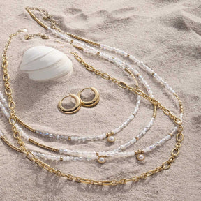 Halskette SOLVANI gold mit Perlen und Ohrringen auf Sand