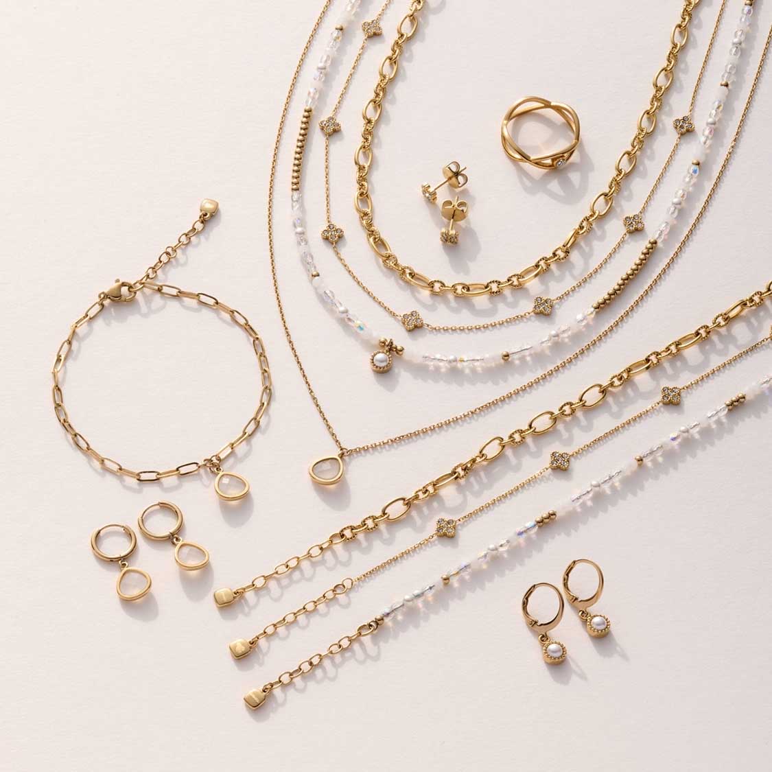 Goldene Schmuckkollektion mit Armbändern, Ketten und Ringen auf hellem Untergrund