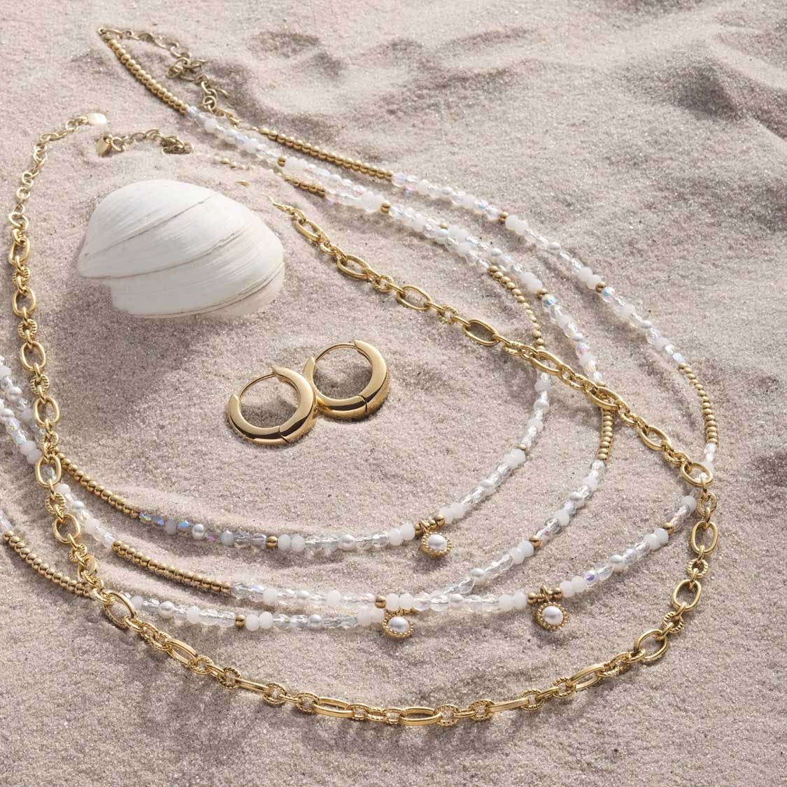 Halskette ALTHINA mit Perlen und goldenen Kettengliedern, Muschel und Ohrringe im Sand