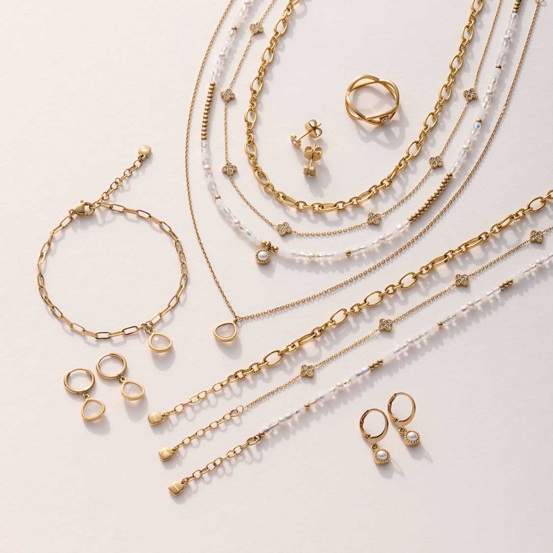 Goldene Halsketten, Armbänder, Ringe und Ohrringe mit Perlen auf hellem Untergrund angeordnet