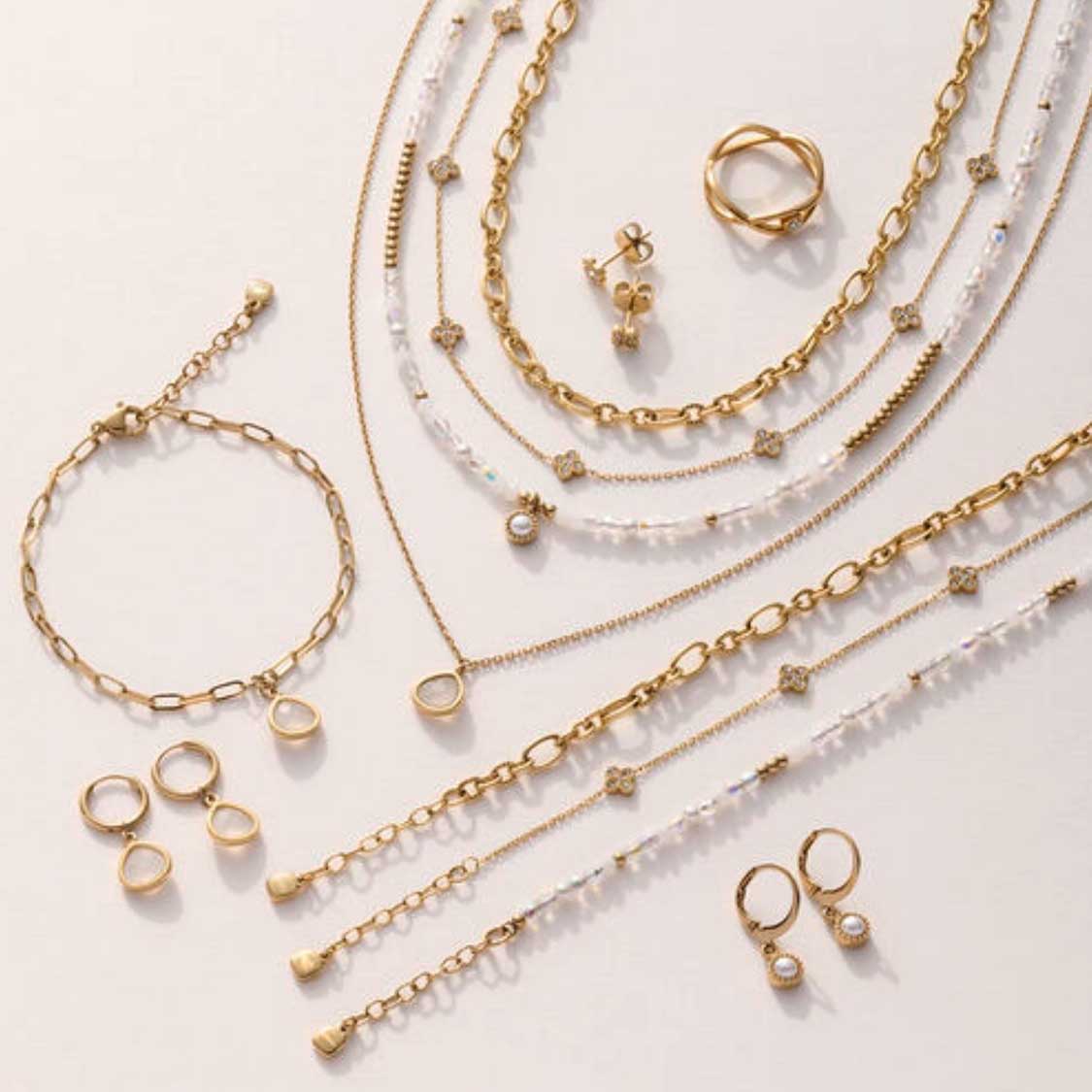 Schmuckkollektion ALTHINA gold mit Ohrringen, Ringen, Ketten und Armbändern auf hellem Hintergrund