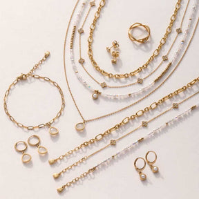 Schmuckkollektion ALTHINA gold mit Ohrringen, Ringen, Ketten und Armbändern auf hellem Hintergrund