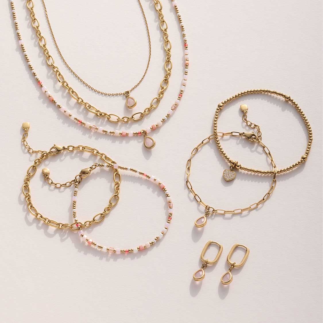 Armbänder und Ohrringe der Serie SHARI gold in Weiß, Rosa und Gold auf hellem Untergrund