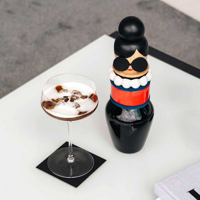 Objektvase BUONI AMICI Sophia auf weißem Tisch neben Cocktailglas und Deko-Figur
