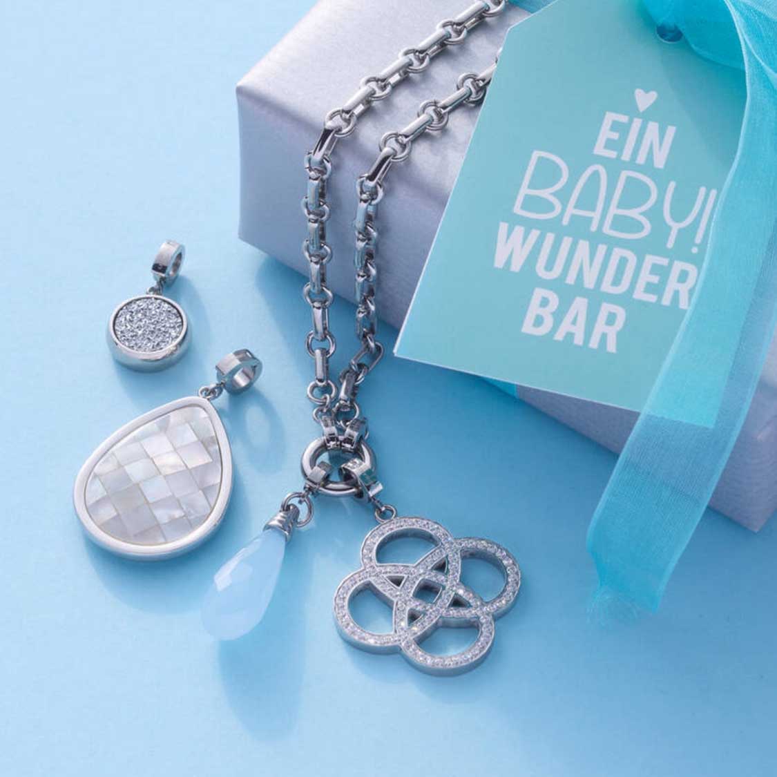 Anhänger FRISCO Clip & Mix mit Kette und austauschbaren Charms auf blauem Hintergrund