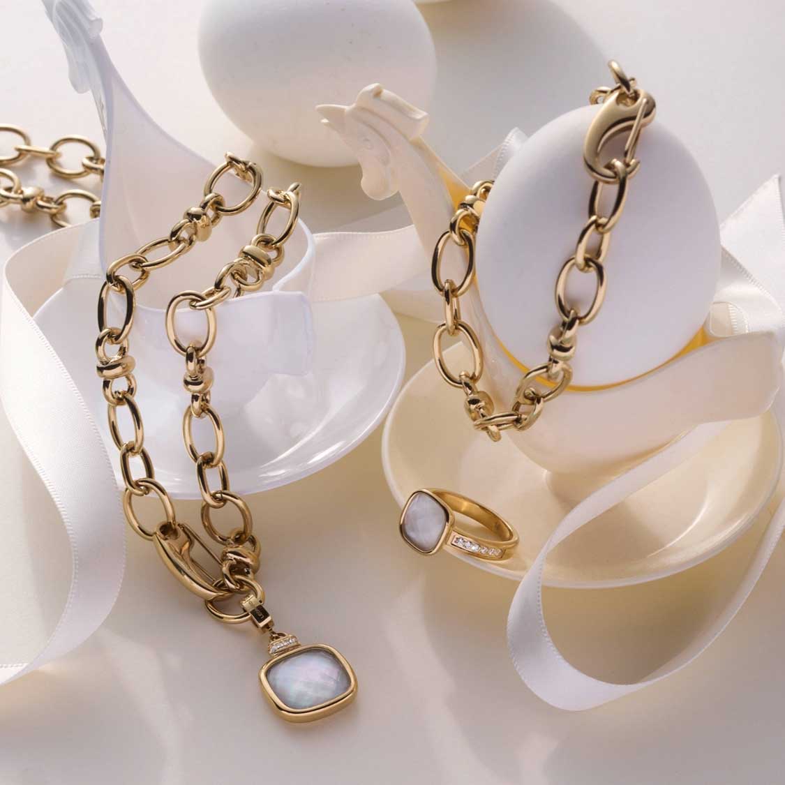 Goldene Kette und Ring VIRGINIA 18 gold auf weißen Dekorationsobjekten